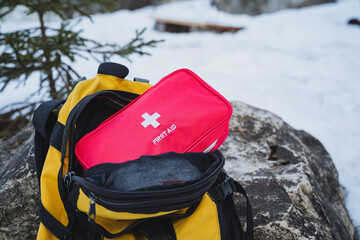 A bright red first aid kit is conveniently placed inside a vibrant yellow backpack, ready for any...