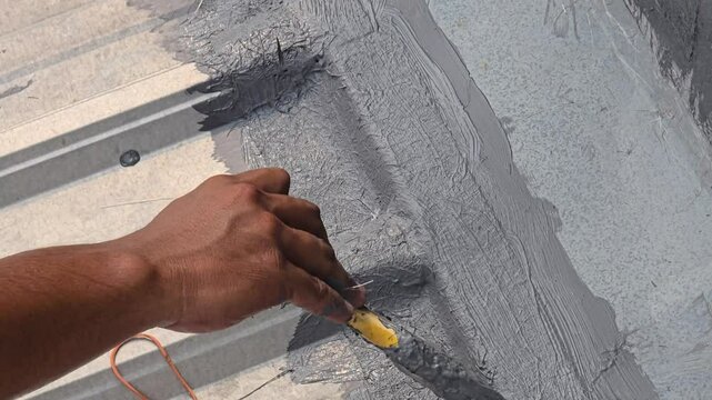 construction worker's hands repairing a leaking roof using anti-leak roof coating paint