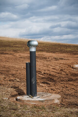 A long pipe is positioned right in the center of a sprawling dirt field, surrounded by barren land,...