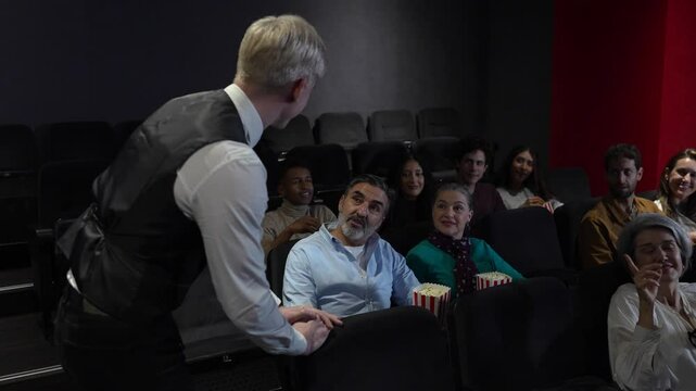 Usher helping couple find seats in a crowded movie theater