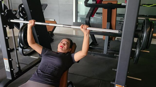 Asian woman doing chest press exercise with smith machine at gym