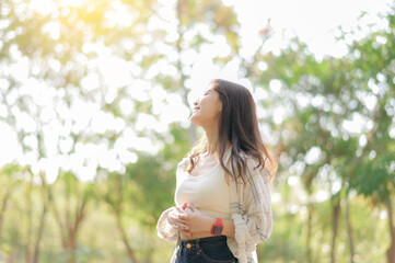 Asian woman enjoying summer while breathing fresh air in sunny park, feeling relaxed and happy...