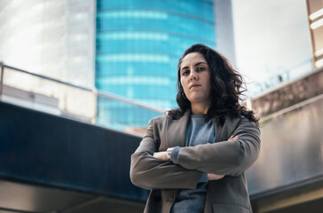 Confident businesswoman crossing arms in modern city setting