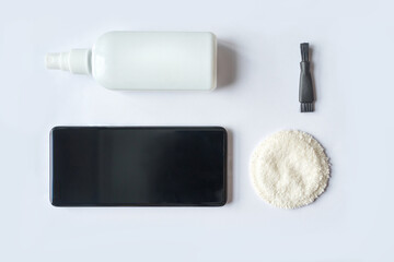 Smartphone screen cleaning kit with spray bottle, black brush, and white cleaning pad on white...