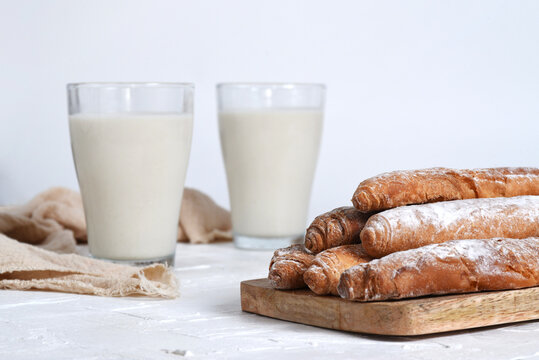 Photographs of tigernut horchata served in glass cups, accompanied by fartons on a wooden board. Ideal for illustrating Valencian gastronomy and traditional cuisine.