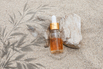 A bottle of serum skincare rests on a sandy surface, capturing the essence of radiant skin care inspired by the calm of the beach.