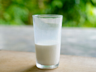 A glass filled with half of fresh milk stands on a bokeh background. Fresh milk for healthy life