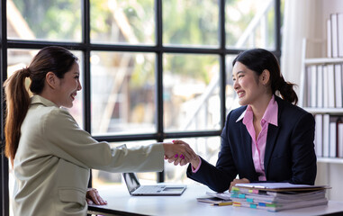 Businesswoman shaking hands with business partner in the office. Woman join hands in a meeting to congratulate their colleagues and cooperate in work.
