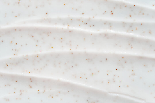 Smooth white cream texture with exfoliating brown specks for skincare and beauty products.