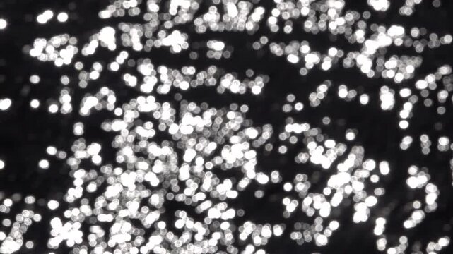 Vue sur des points lumineux de reflets du soleil sur l'eau avec effet flou d'objectif