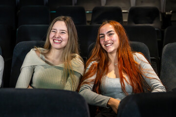 Two young women smiling and enjoying a movie at the cinema