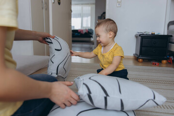 Mother and her two year old son playing in a children room, symbolizing motherhood and care