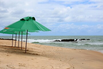 Summer vacations on tropical beach. Green parasol waiting for tourists, travel destination, Coqueiros beach, Joao Pessoa city, Paraaba, Brazil northeast.