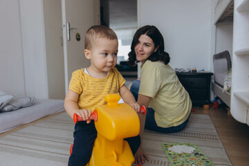 Mother and her two year old son playing in a children room, symbolizing motherhood and care