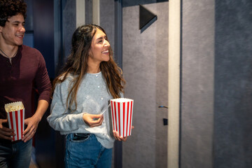 Young couple entering movie theater with popcorn and tickets
