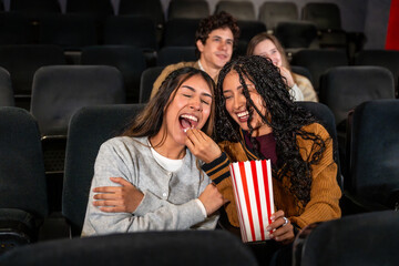 Friends laughing and sharing popcorn at the movie theater