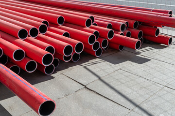 Stack of new, red, plastic, even, long pipelines. PE, HDPE tubes.