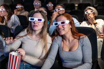 Young women enjoying 3d movie with popcorn in cinema
