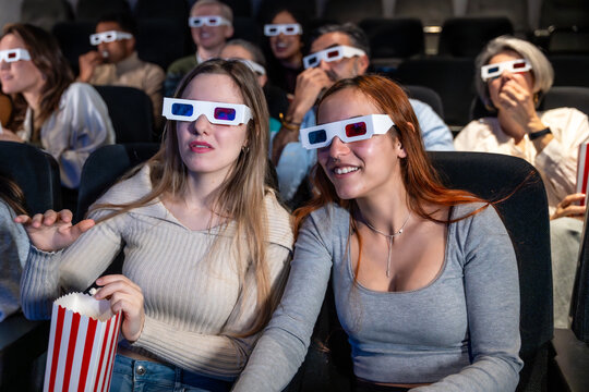 Young women enjoying 3d movie with popcorn in cinema