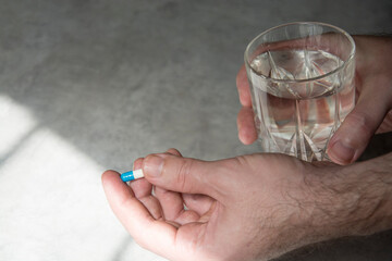 Hand holding pill and a glass of water
