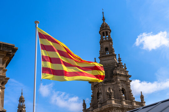 Flying flag of Catalonia on top of National Art Museum of Catalonia with the tower and blue sky in background in summer, Barcelona, Spain
