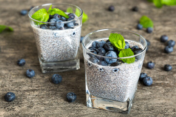 Healthy breakfast or morning with chia seeds vanilla pudding and blueberry berries on table background, vegetarian food, diet and health concept. Chia pudding with coconut milk and blueberry