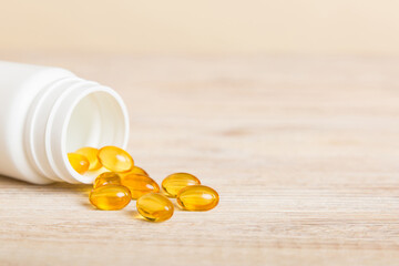 Soft gels pills with Omega-3 oil spilling out of pill bottle close-up. Gel capsules bottle white...