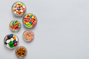 different colored round candy in bowl and jars. Top view of large variety sweets and candies with copy space