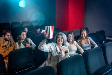 Woman holding popcorn bucket watching movie in theater