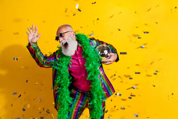 Fototapeta premium Photo of elderly cool old man dancing disco confetti wear stylish striped suit boa sunglass isolated on yellow color background
