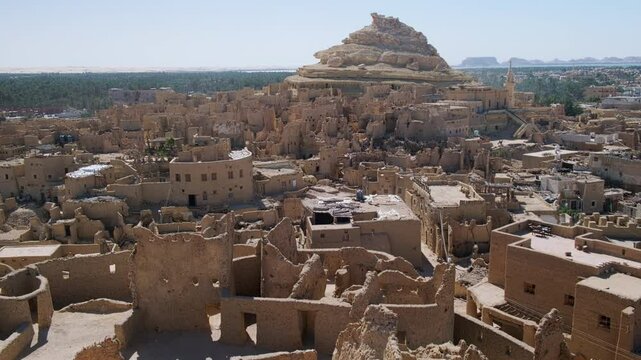 Remains of mud-brick houses of Shali fortress and Shali Mountain at background in Siwa Oasis, Egypt