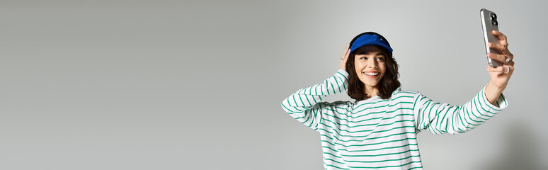 Beautiful young woman enjoys a sunny day while taking a selfie in stylish summer attire