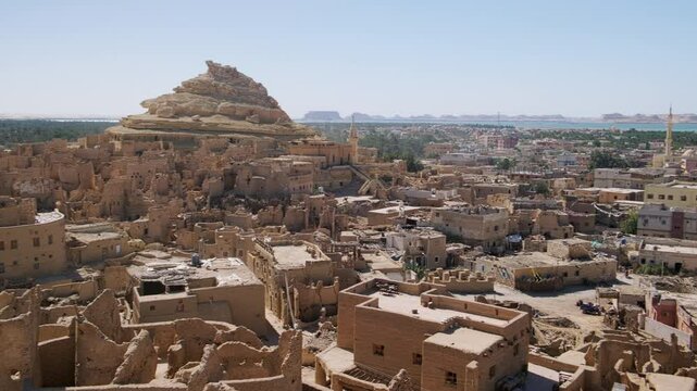 Remains of mud-brick houses of Shali fortress and Shali Mountain at background in Siwa Oasis, Egypt. Panning real time footage
