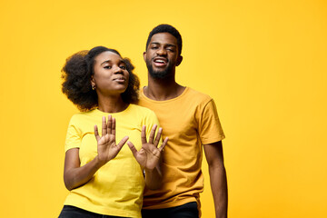 Fototapeta premium Happy young couple in matching yellow outfits, posing playfully against a vibrant yellow background, representing joy, love, and connection