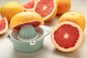 Juicer with freshly squeezed red grapefruit juice,with whole and sliced grapefruit on light...