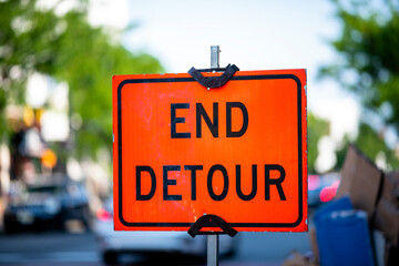 Bright Orange End Detour Sign Against Blurred Street Background in Daylight