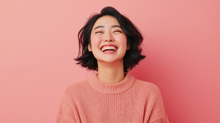 Fototapeta premium Asian woman smiling broadly against a pink background.
