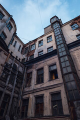 Fototapeta premium The dilapidated facade of old city buildings and the blue sky above.