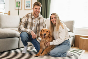 Portrait of a young couple on the livingroom with golden retriever dog indoors at home.