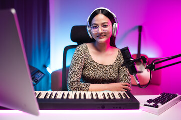 Asian teen girl playing guitar, composing music in home recording studio, LED lighting, at night...