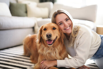 Portrait of a young woman on the livingroom with golden retriever dog indoors at home.