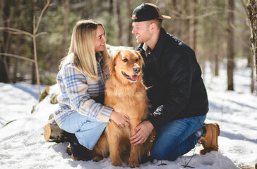 Portrait of a young couple outside on spring season with golden retriever dog