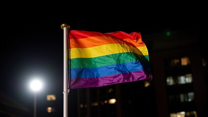 Fototapeta premium Vibrant pride flag shining with LED lights in urban night setting Symbol of diversity love and equality Perfect for LGBTQ concepts