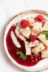 Lazy dumplings, vareniki with raspberry jam decorated with raspberry and mint leaves. Boiled cottage cheese homemade gnocchi.
