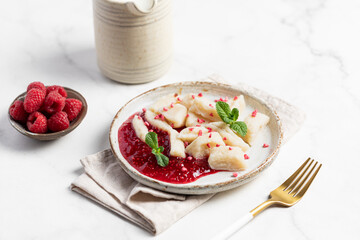 Lazy dumplings, vareniki with raspberry jam decorated with raspberry and mint leaves. Boiled cottage cheese homemade gnocchi.