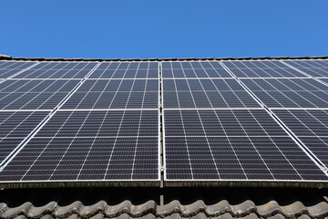 Photovoltaic panels providing clean energy on rooftop against blue sky