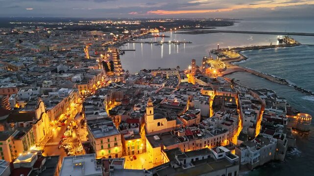 Embankment and old town with city lights in Molfetta. Aerial evening view of historic center of Molfetta, in the province of Bari, Puglia 