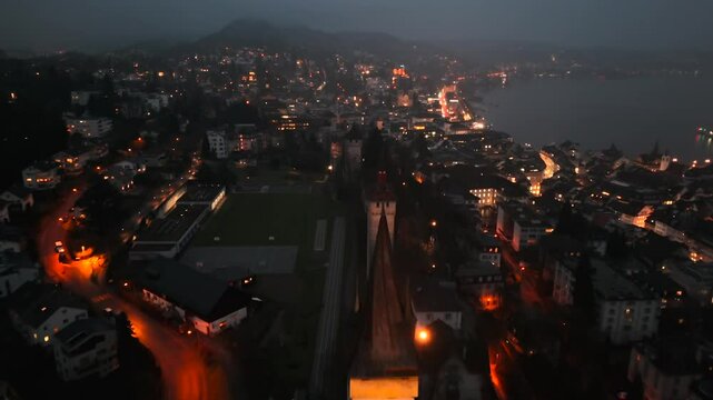 Musegg Wall and its nine towers aerial view at night overlooking glowing city in Lucerne, Switzerland. Medieval defenses of Lucerne. Museggmauer Luzern und ihre neun Tuerme Luftaufnahme bei Nacht. 