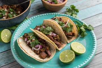 Top view of four tasty tacos with lime wedges on turquoise plate, Mexican cuisine, ready to eat.