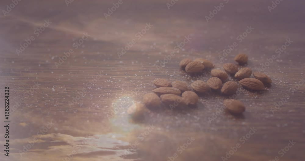 Poster scattered almonds on wooden surface with soft light creating reflections